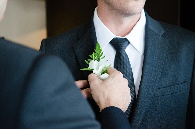 白い花をつけるスーツの男